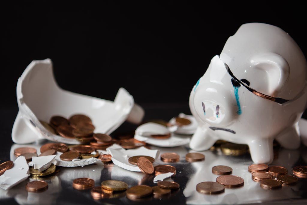 Münzgeld und zerstörtes, weinendes Sparschwein